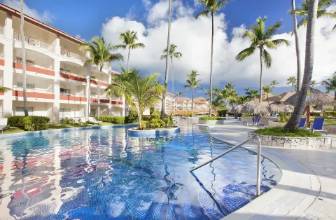 Swim-up style pool beside guest buildings and palapas at Majestic Elegance Punta Cana.