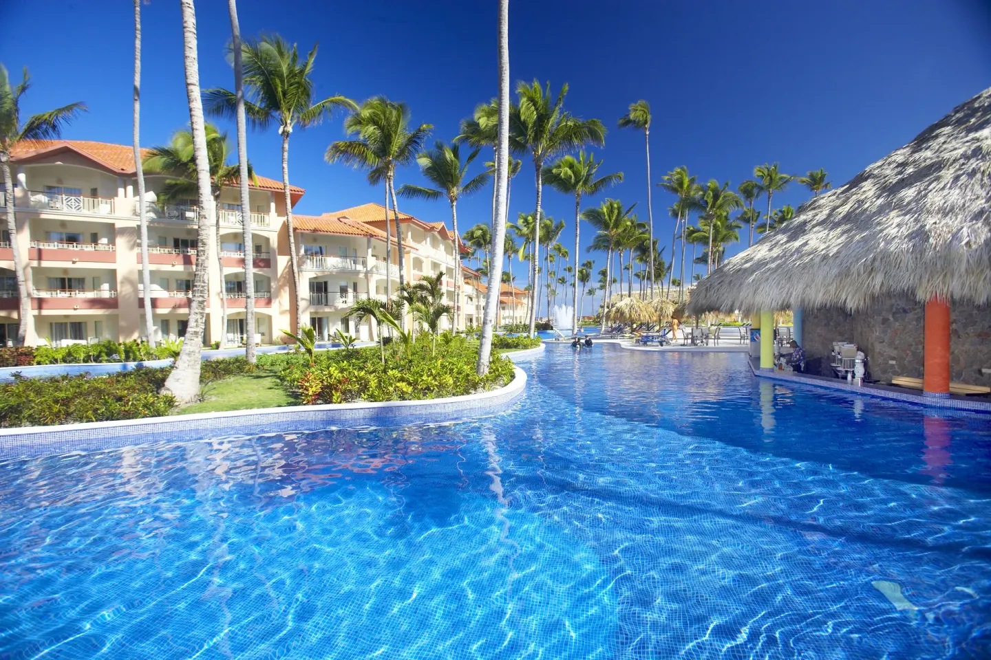 Large pool beside a thatched swim-up area at Majestic Elegance Punta Cana.