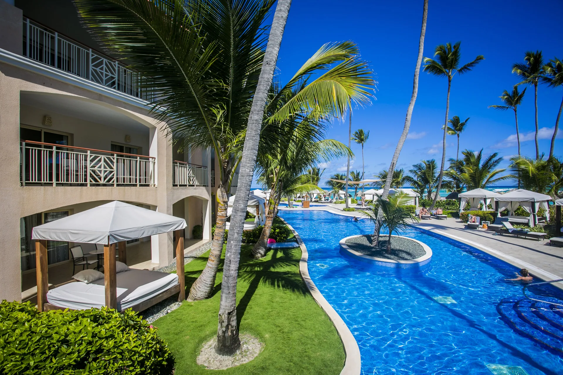 Poolside guest room building at Majestic Elegance Punta Cana with cabanas, palms and swim-up pool.