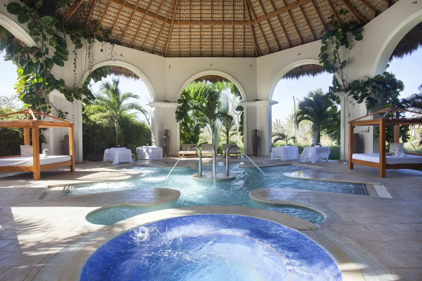 A thatched spa pavilion shelters pools and daybeds at Majestic Elegance Punta Cana.