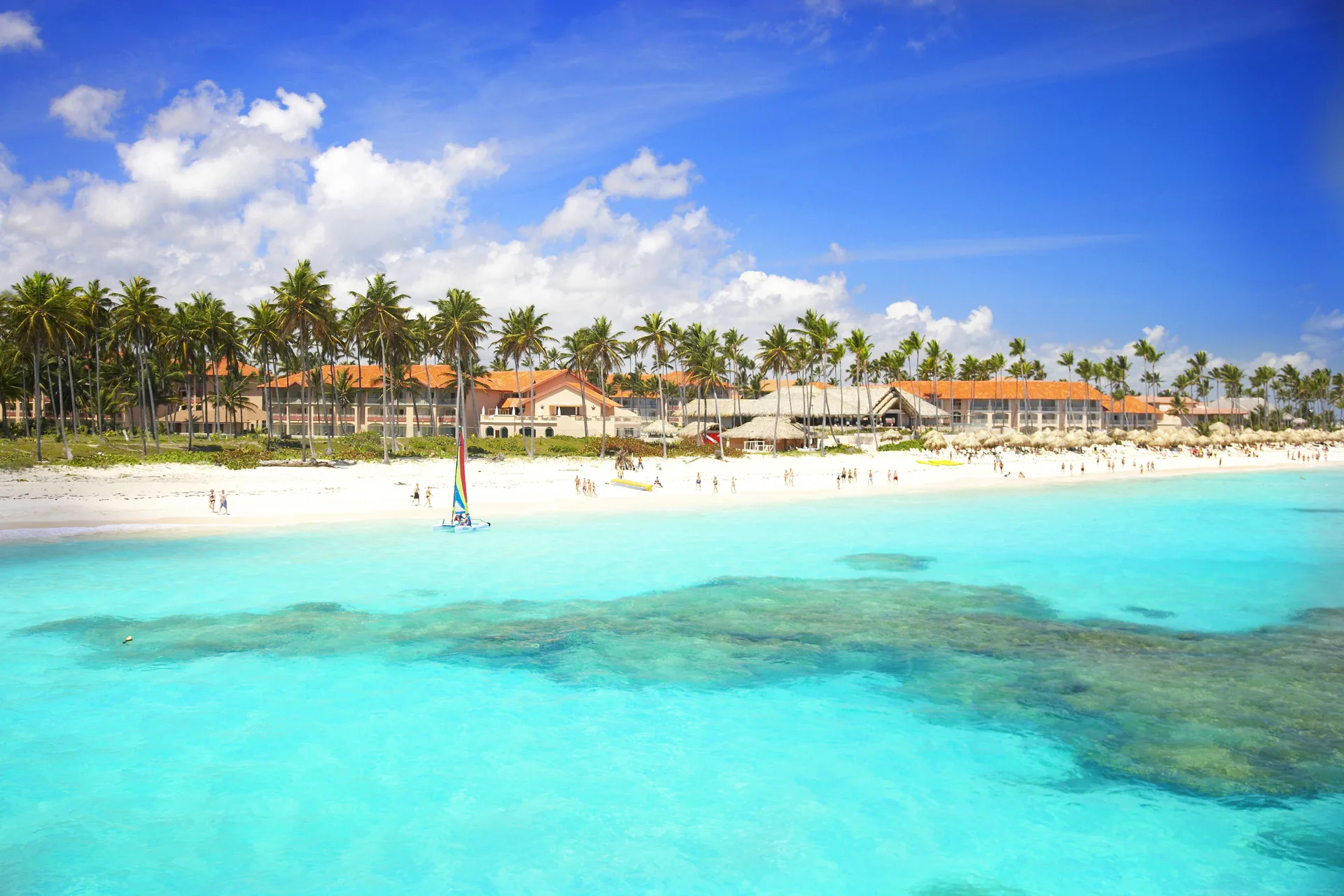 Wide beach and turquoise water with resort buildings behind at Majestic Elegance Punta Cana.