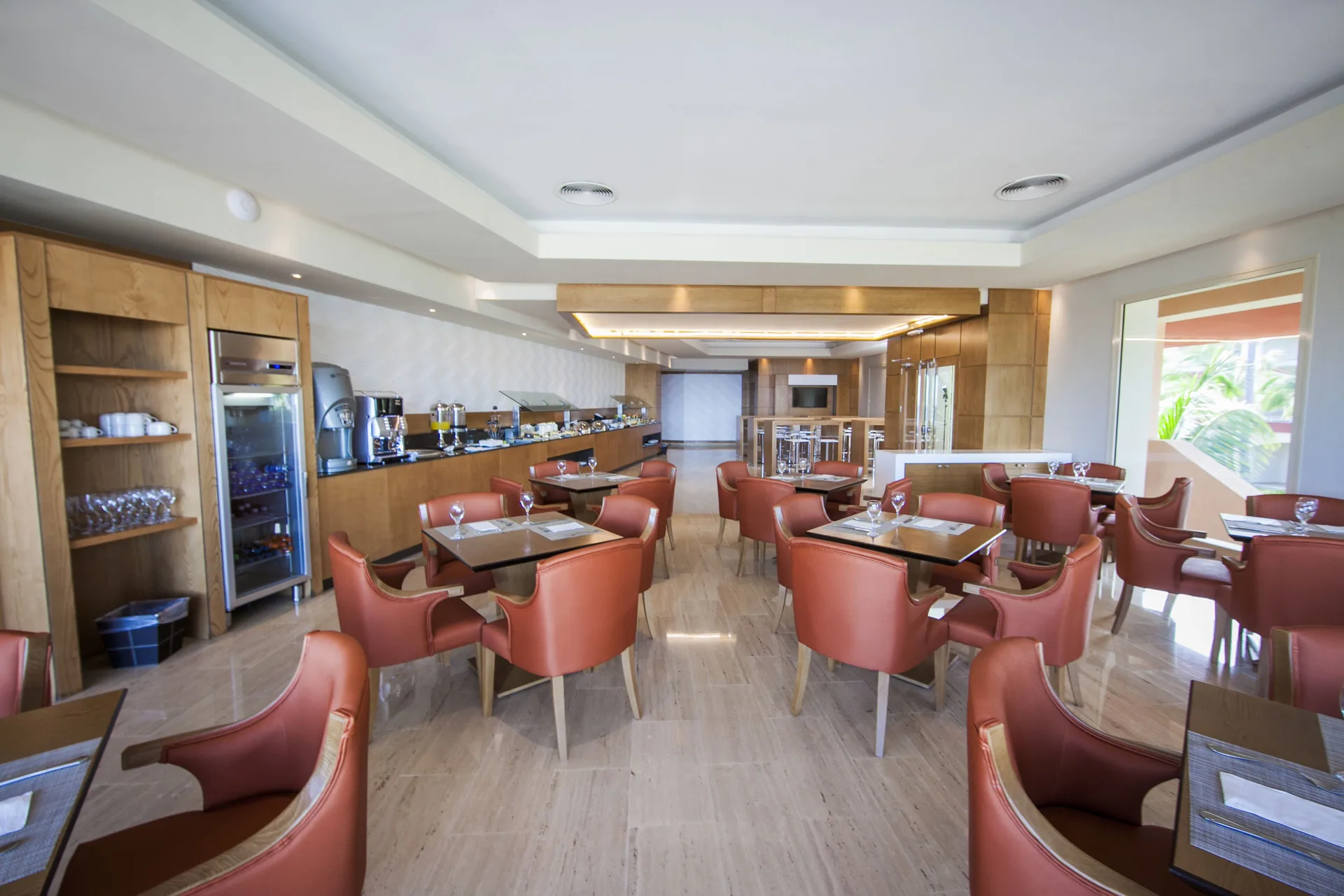 Bright dining room with coral chairs and buffet counter at Majestic Elegance Punta Cana.