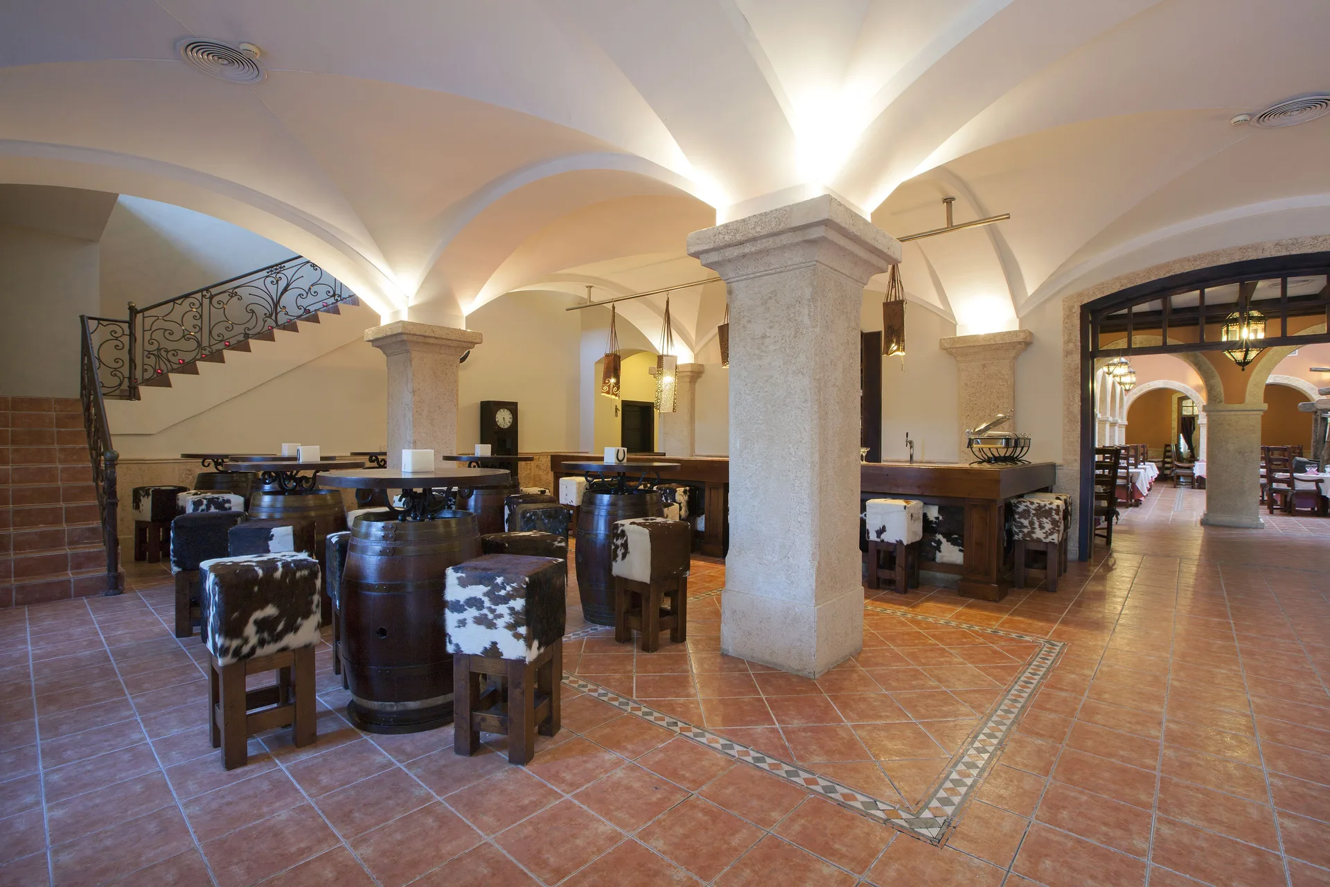 Barrel tables and cowhide stools in a vaulted bar at Majestic Elegance Punta Cana.