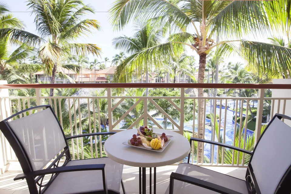 Colonial Junior Suite balcony seating with palm and pool views at Majestic Elegance Punta Cana.