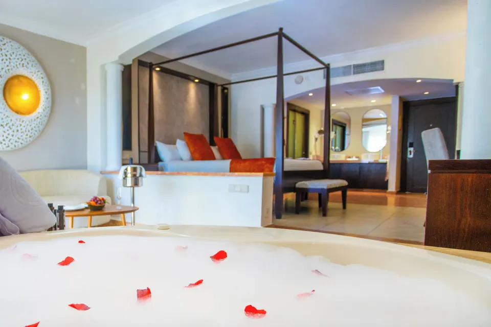 Jacuzzi tub with rose petals facing the king bed at Majestic Elegance Punta Cana.