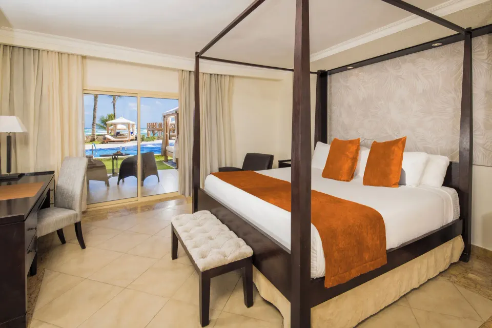 King bed with orange accents and pool view at Majestic Elegance Punta Cana.