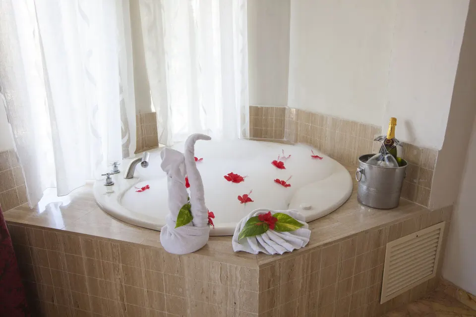 Junior Suite Jacuzzi with towel swan and flower petals at Majestic Elegance Punta Cana.