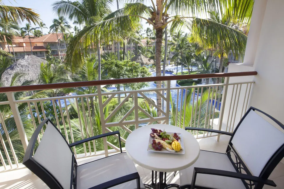 Junior Suite balcony with table and palm garden view at Majestic Elegance Punta Cana.