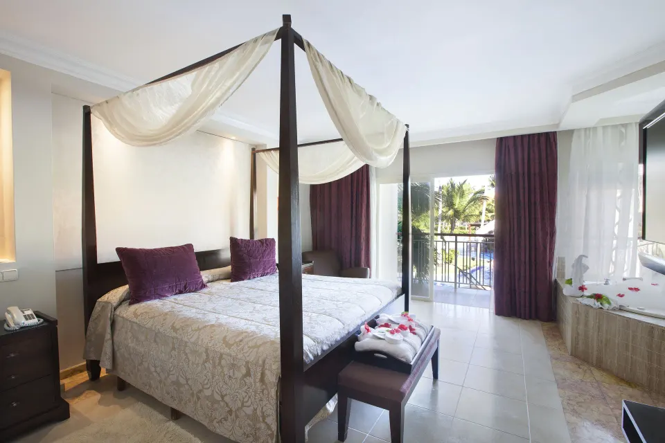 Junior Suite with Jacuzzi, balcony doors, and canopy bed at Majestic Elegance Punta Cana.