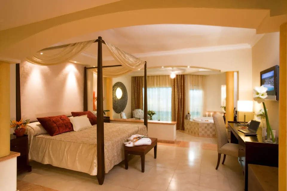 Warmly lit Junior Suite with Jacuzzi and canopy bed at Majestic Elegance Punta Cana.