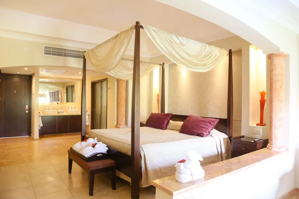 Junior Suite canopy bed and vanity area at Majestic Elegance Punta Cana.