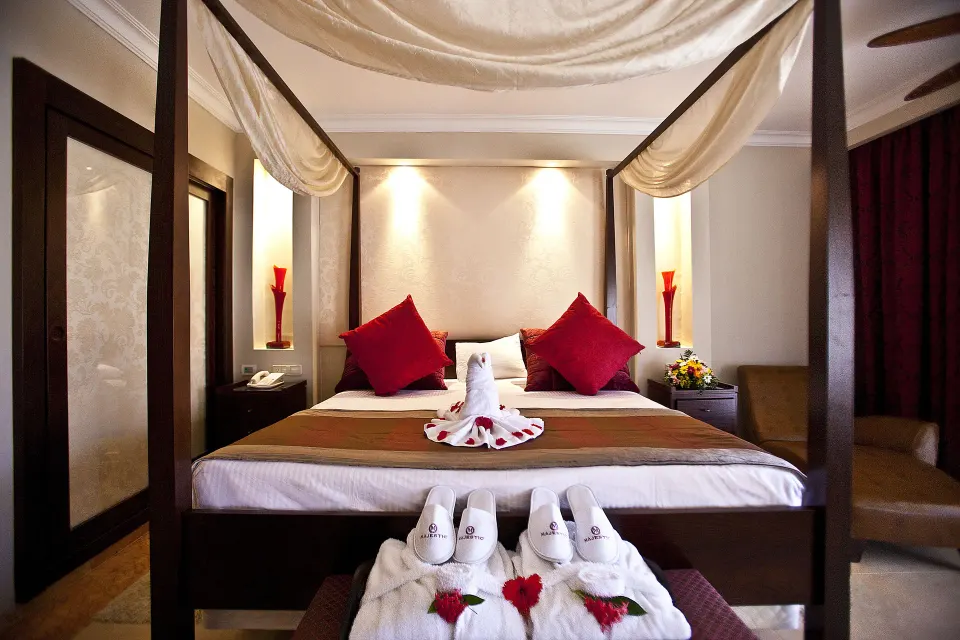One Bedroom Suite king canopy bed at Majestic Elegance Punta Cana with robes and towel swan decor.