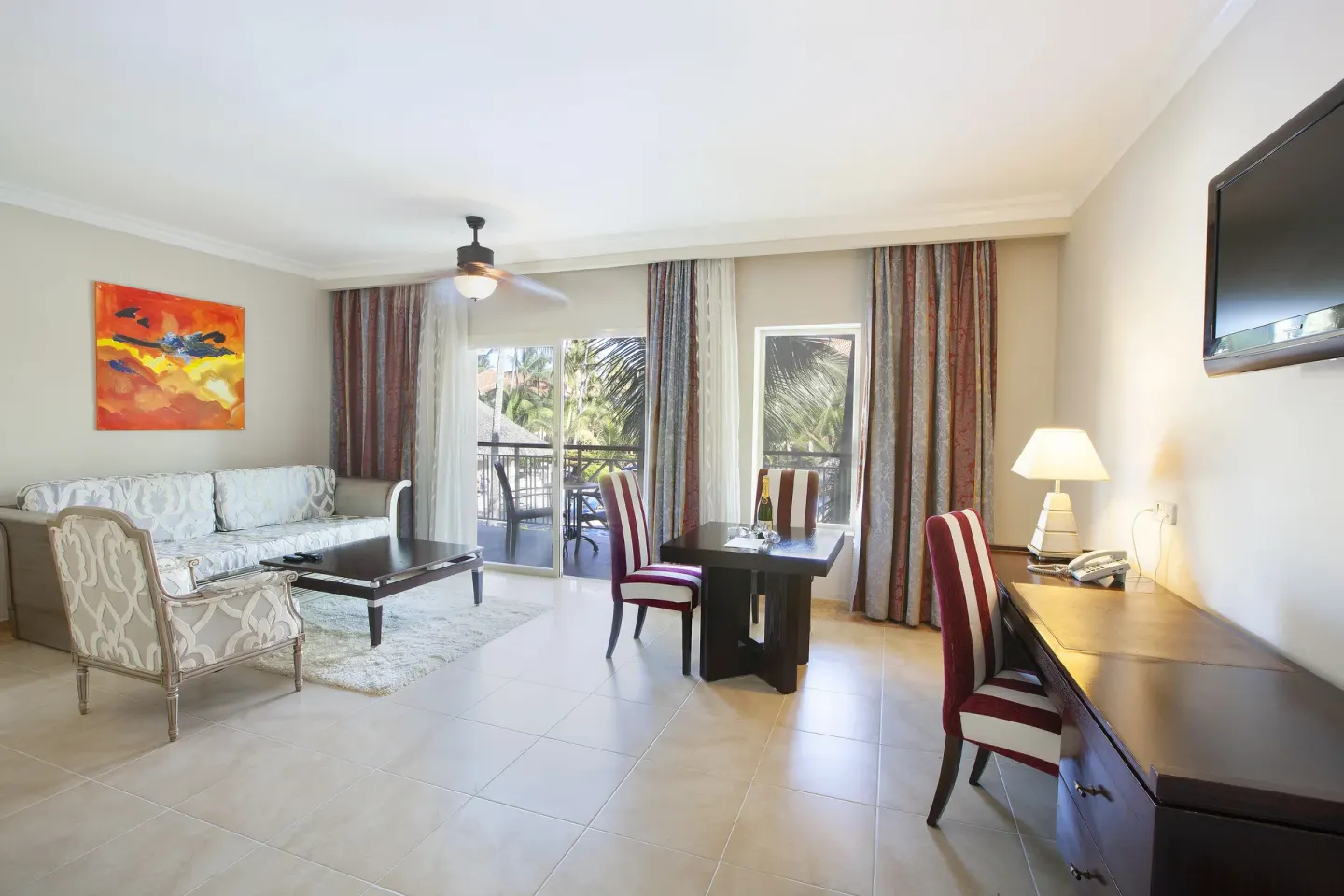 One Bedroom Suite living area at Majestic Elegance Punta Cana with sofa, dining table, desk, and balcony.