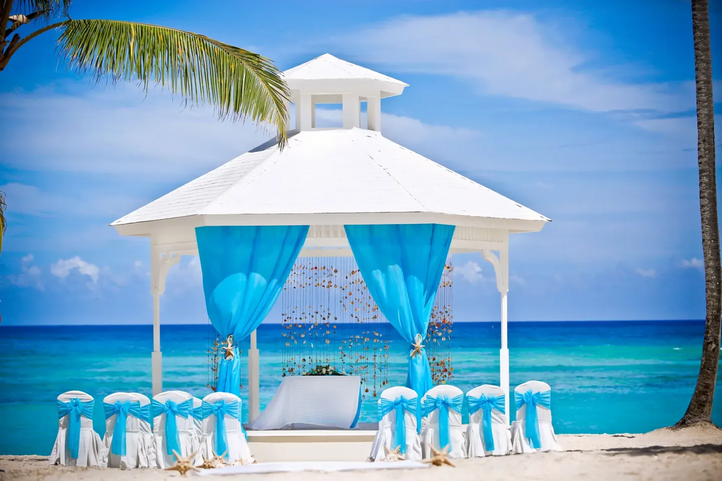 Beach wedding gazebo at Majestic Elegance Punta Cana with turquoise drapes and ocean backdrop.