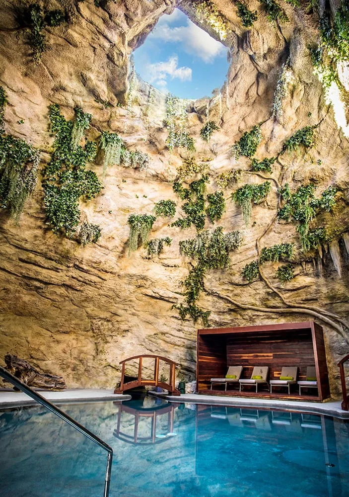 Cave-style indoor pool with rock walls and lounge chairs at Majestic Mirage Costa Mujeres.