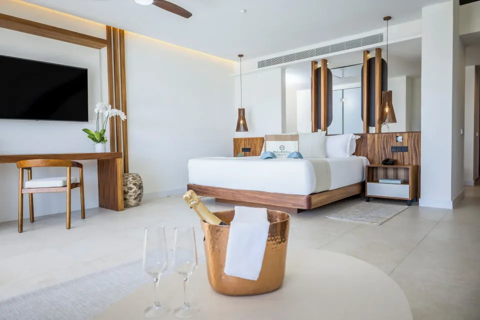 Family Club Plunge Pool Suite king bedroom at Majestic Mirage Costa Mujeres with desk and wall-mounted TV.
