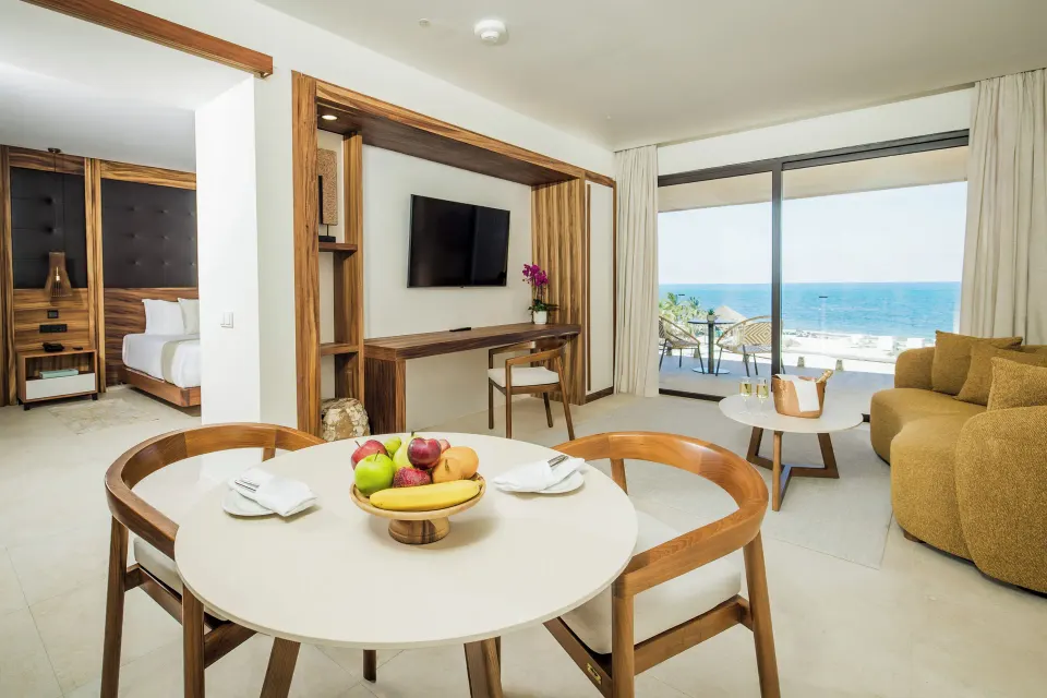 Mirage Club Oceanfront Suite living area with king bed and balcony at Majestic Mirage Costa Mujeres.