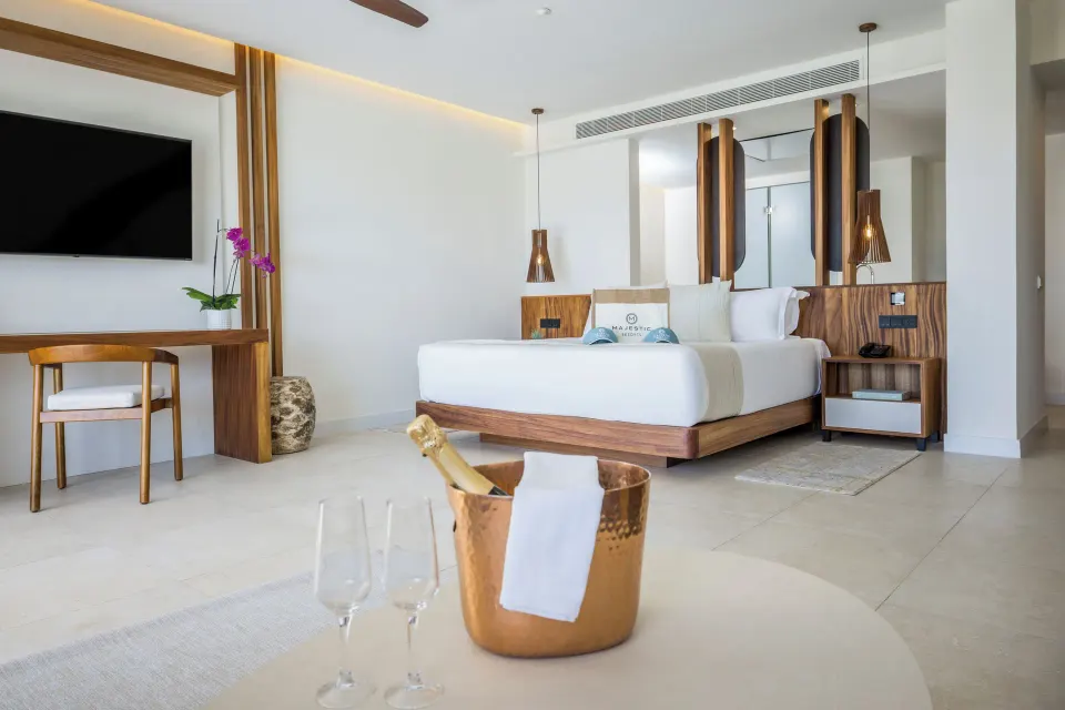 King bed suite with TV, desk, and champagne bucket at Majestic Mirage Costa Mujeres.