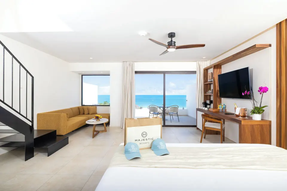 King bed suite with staircase, lounge area, and ocean balcony at Majestic Mirage Costa Mujeres.