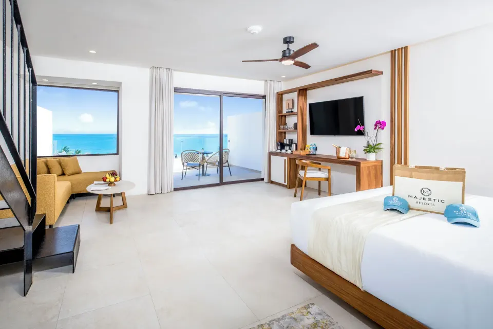 Oceanfront suite with king bed, sofa, balcony, and TV at Majestic Mirage Costa Mujeres.