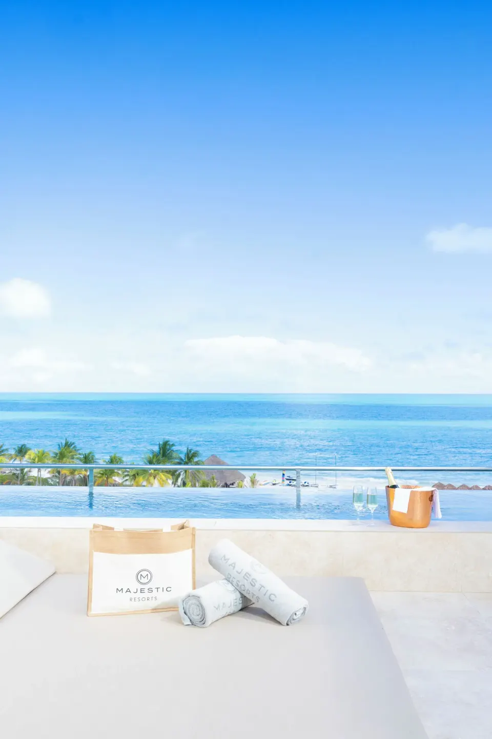 Oceanfront plunge pool terrace at Majestic Mirage Costa Mujeres with towels, tote bag, and sea view.