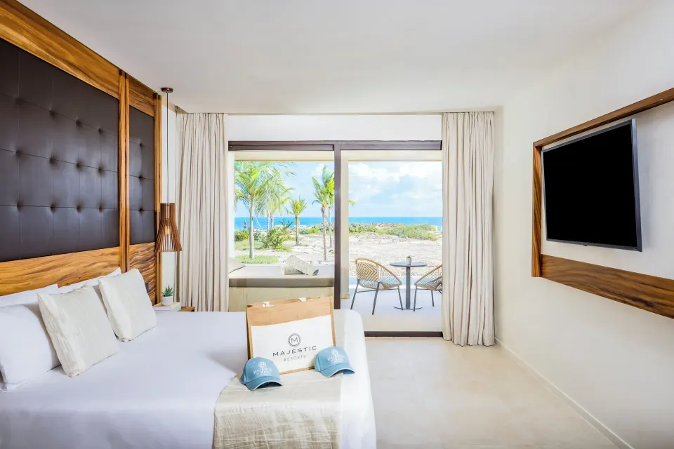King bed facing an oceanfront terrace in a swim-up suite at Majestic Mirage Costa Mujeres.