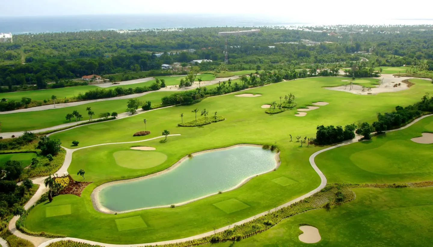 An aerial view of a golf course and lake near Majestic Mirage Punta Cana.