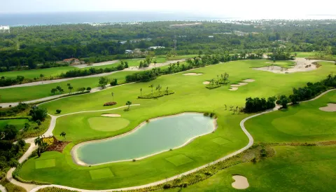 An aerial view of a golf course and lake near Majestic Mirage Punta Cana.