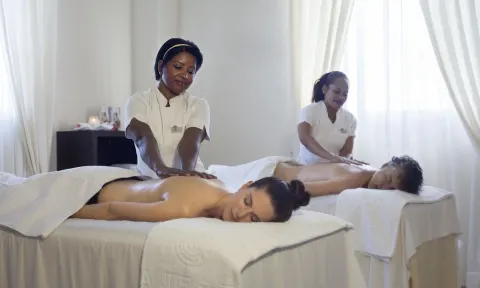 Two guests receive massages in a bright spa room at Majestic Mirage Punta Cana.