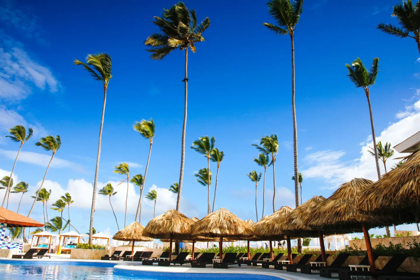 Curving pool with palapas, loungers, and palm trees at Majestic Mirage Punta Cana.
