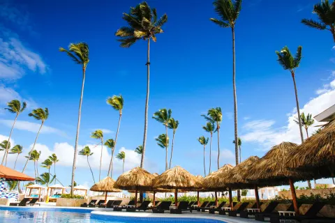 Curving pool with palapas, loungers, and palm trees at Majestic Mirage Punta Cana.