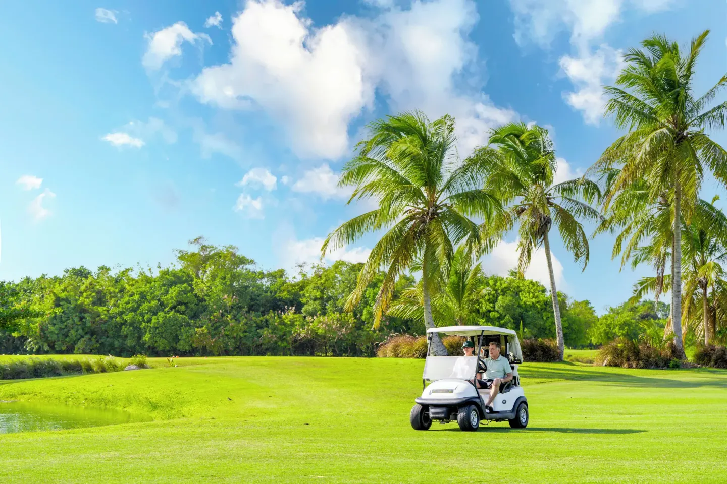 Golfers ride a cart across a palm-framed fairway at Majestic Mirage Punta Cana.
