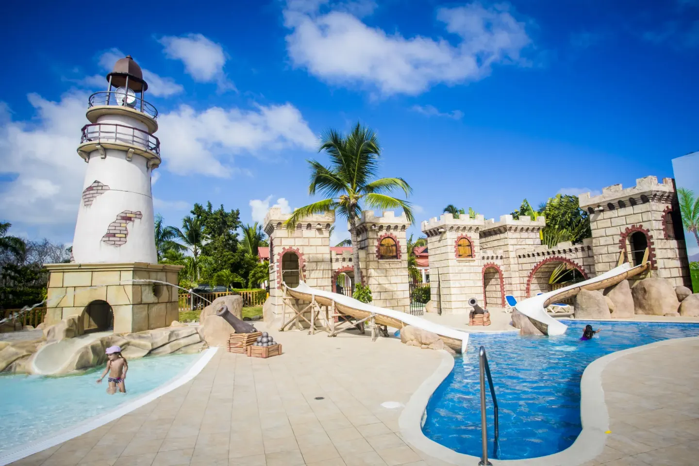 A kids pool with a lighthouse, castle walls, and water slides at Majestic Mirage Punta Cana.