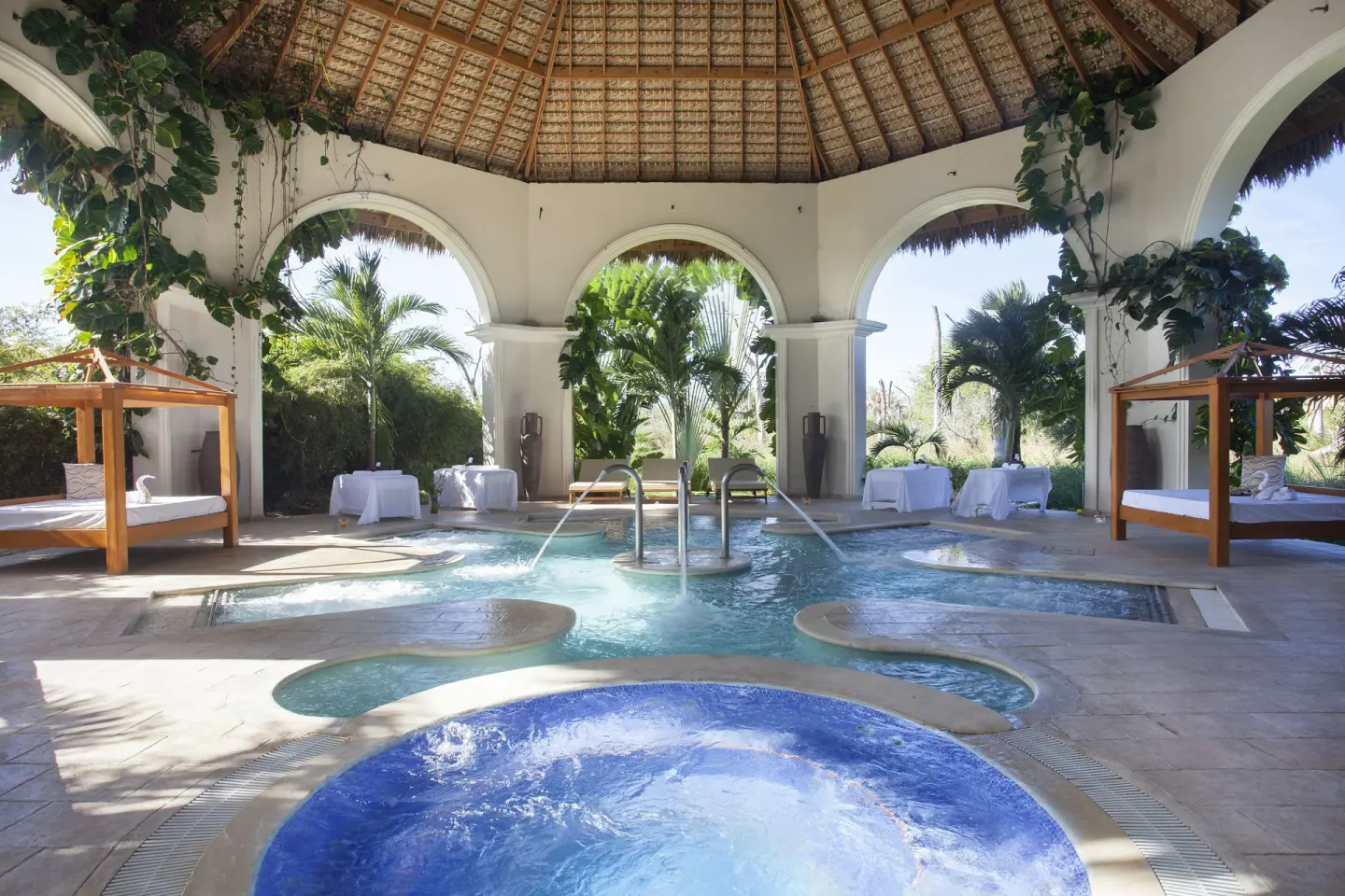 Open-air spa hydrotherapy pool under a thatched roof at Majestic Mirage Punta Cana.