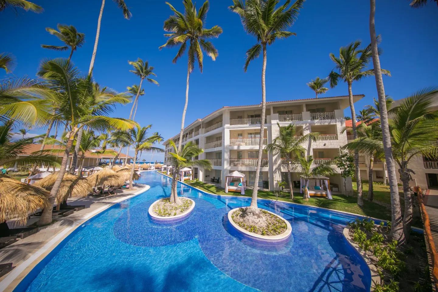 Expansive blue pool winding past balconies and palm islands at Majestic Mirage Punta Cana.
