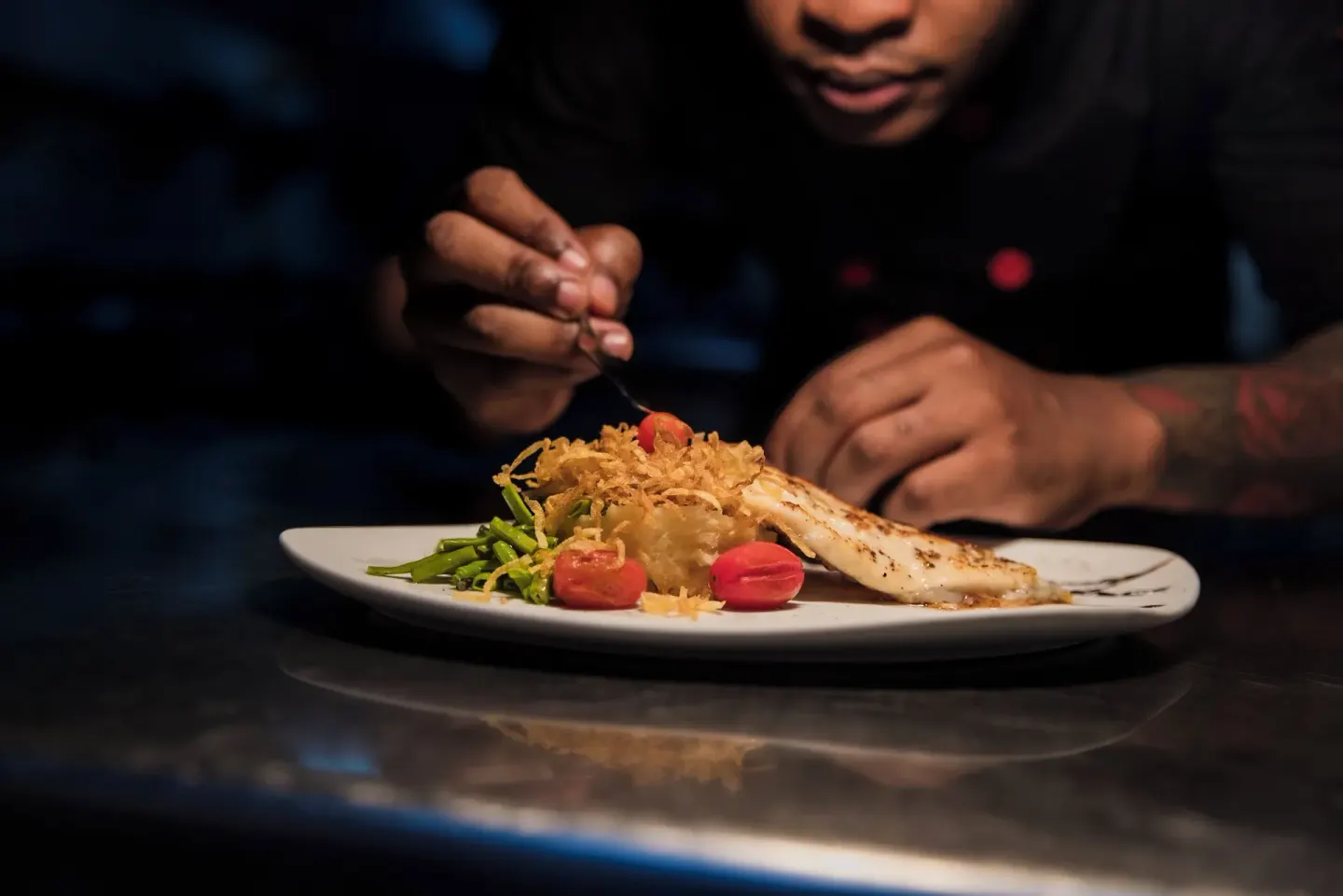 Chef adding garnish to a fish dish on a white plate at Majestic Mirage Punta Cana.