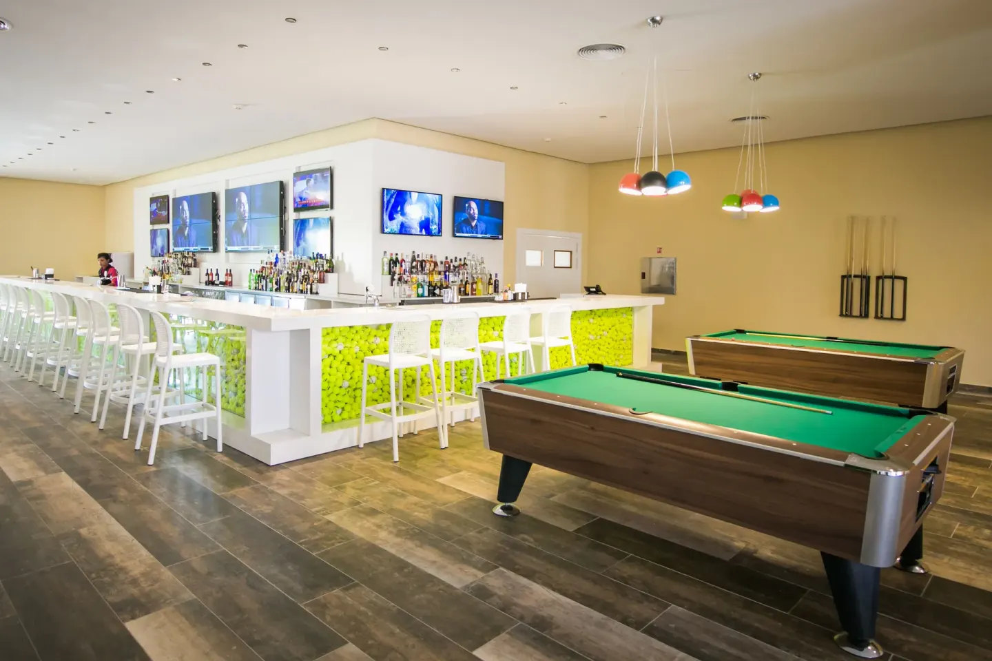 A sports bar with pool tables, TVs, and a long white bar at Majestic Mirage Punta Cana.