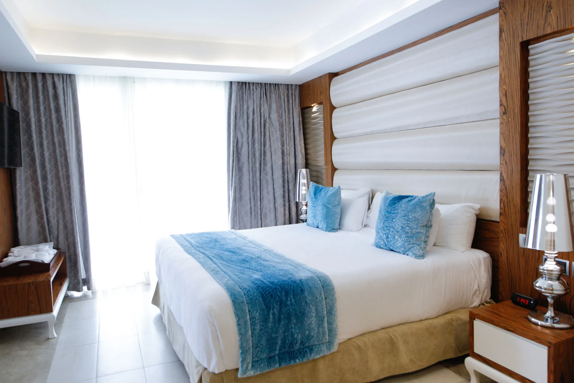 Family Suite king bed with blue accents and bright window at Majestic Mirage Punta Cana.