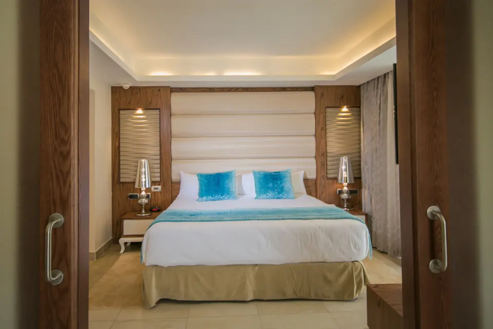 King bed with blue accents seen through sliding doors at Majestic Mirage Punta Cana.