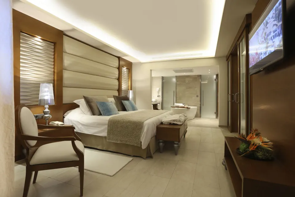 King bed, TV wall, and open bath area in a Mirage Club suite at Majestic Mirage Punta Cana.