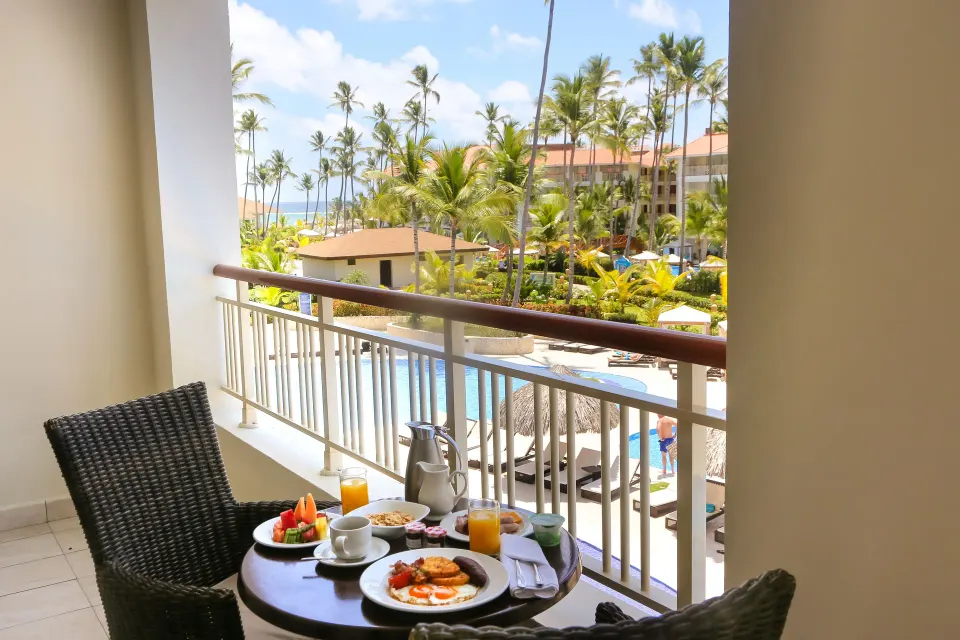 One Bedroom Suite balcony breakfast with pool and palms at Majestic Mirage Punta Cana.