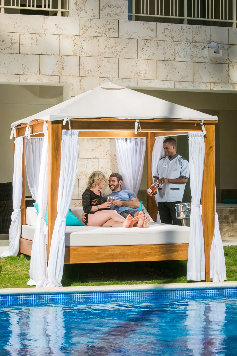 Swim Up Suite poolside daybed with guests and service at Majestic Mirage Punta Cana.