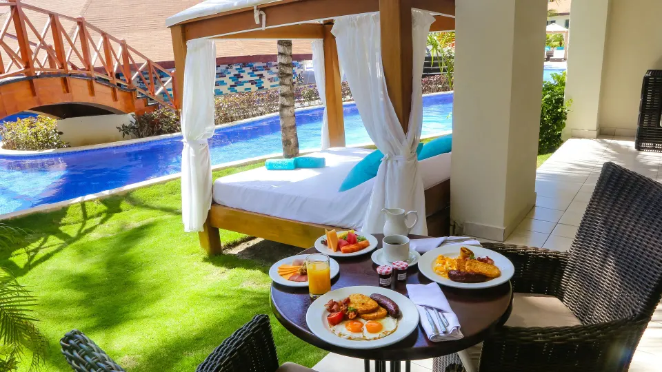 Swim Up Suite terrace with breakfast table and cabana daybed at Majestic Mirage Punta Cana.