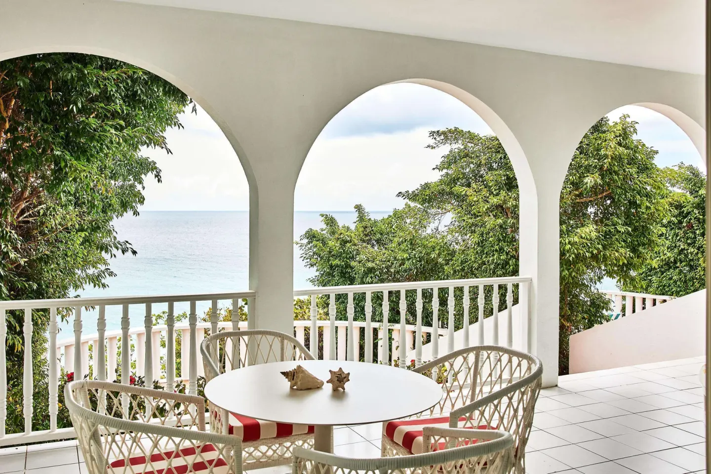 Arched terrace with woven dining chairs and sea views at Malliouhana Resort Anguilla.