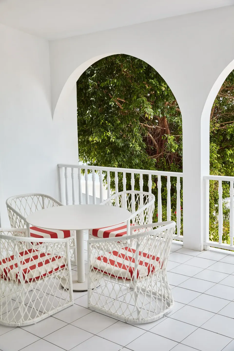 White arched balcony with wicker chairs and greenery at Malliouhana Resort Anguilla.