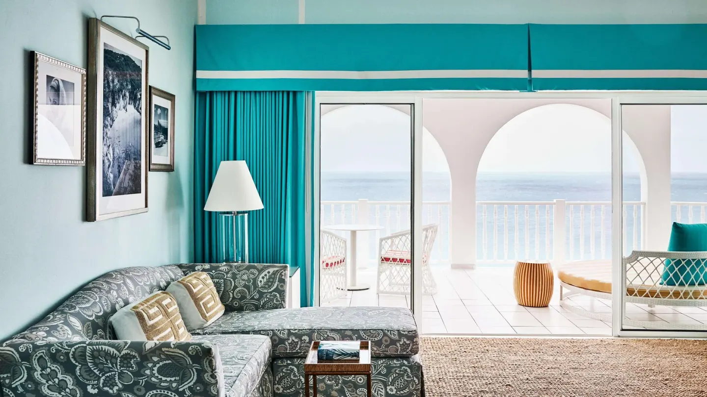Ocean-view sitting area with sofa and balcony at Malliouhana Resort Anguilla.