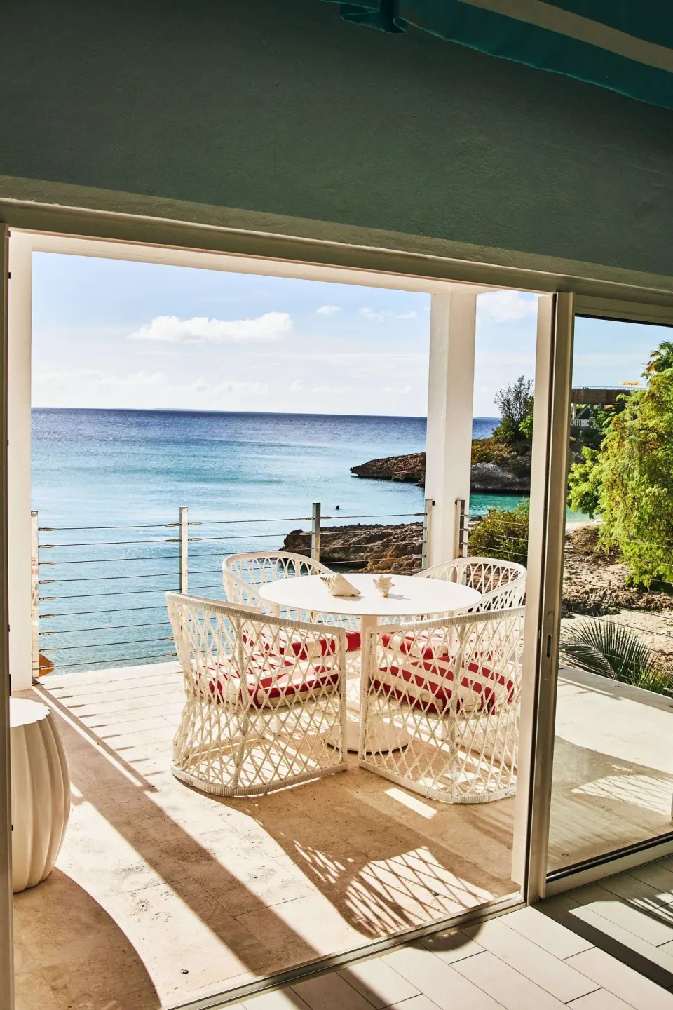 Terrace dining table framed by sliding doors at Malliouhana Resort Anguilla.