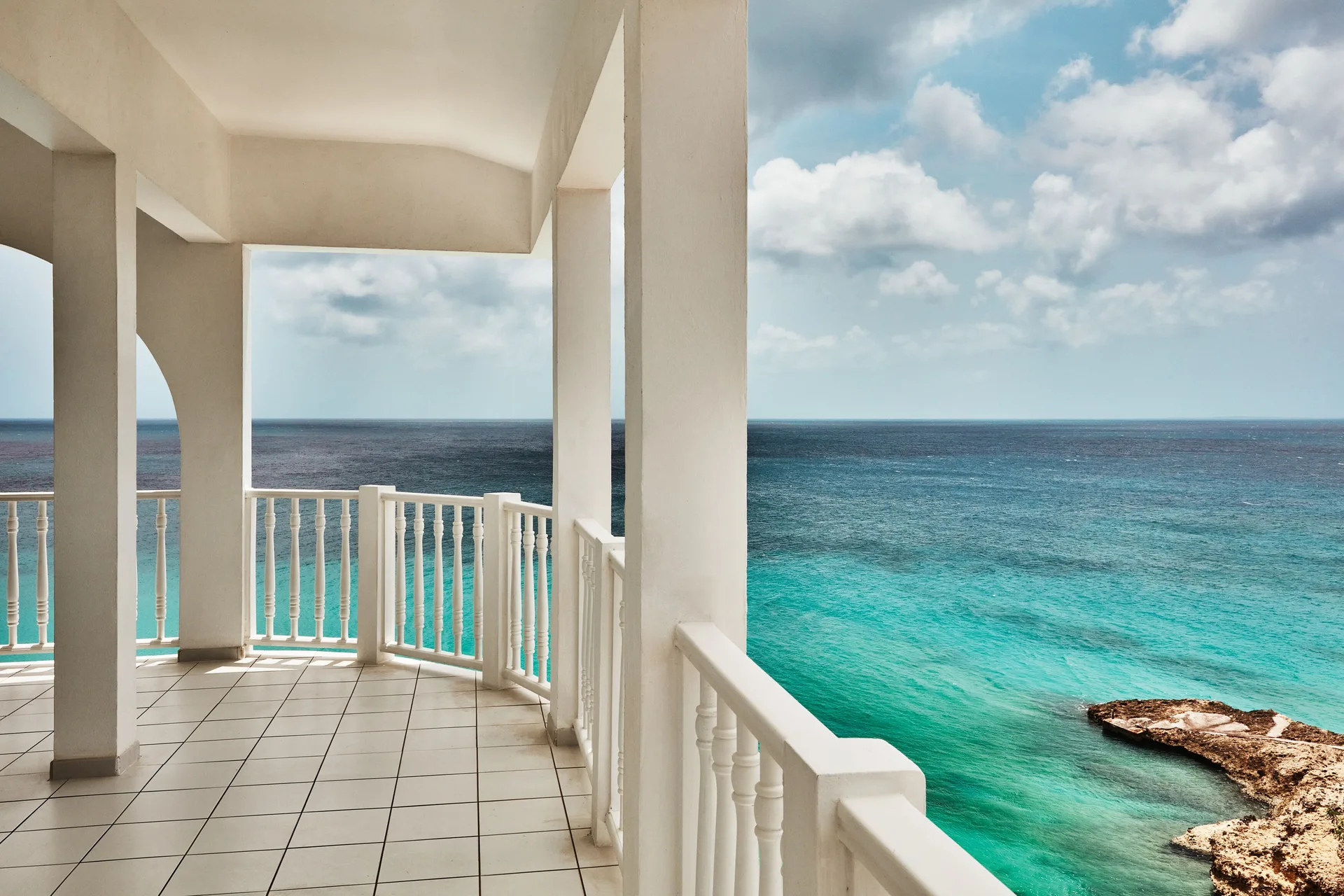 Oceanfront balcony with white railings and turquoise water at Malliouhana Resort Anguilla.