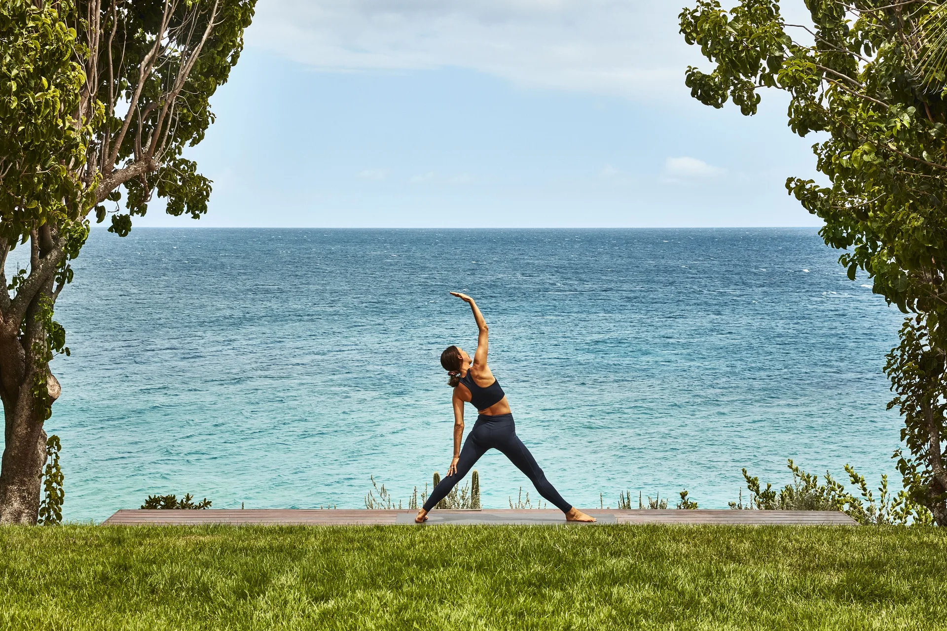 A person practices yoga on a lawn facing the sea at Malliouhana Resort Anguilla.