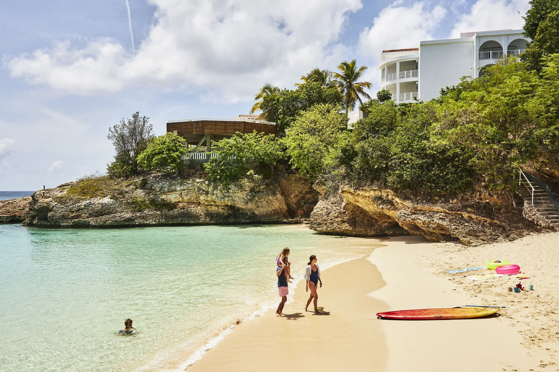 Sandy cove with swimmers and resort buildings at Malliouhana Resort Anguilla.